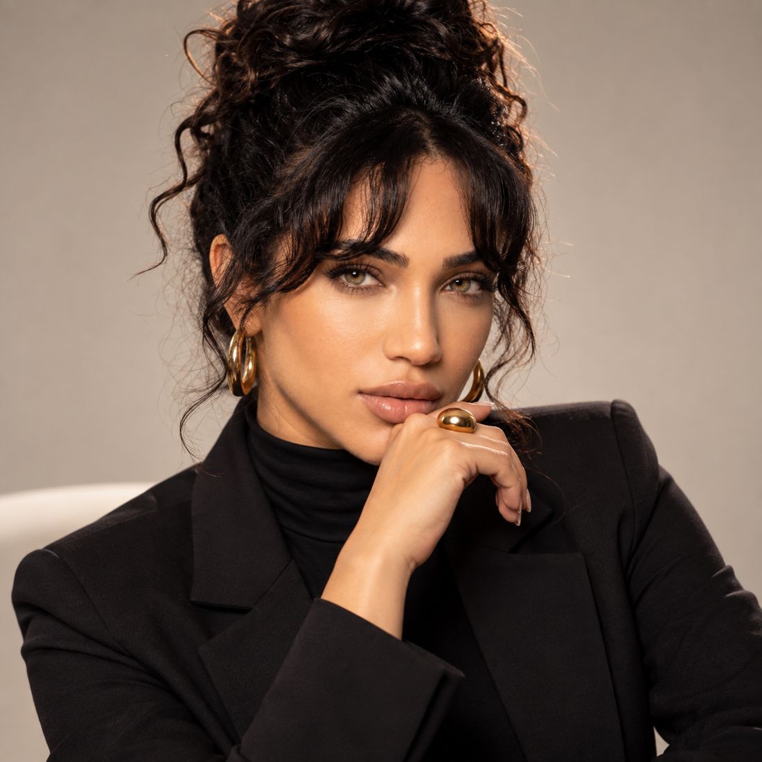 Aishnova founder in a black blazer with gold jewellery